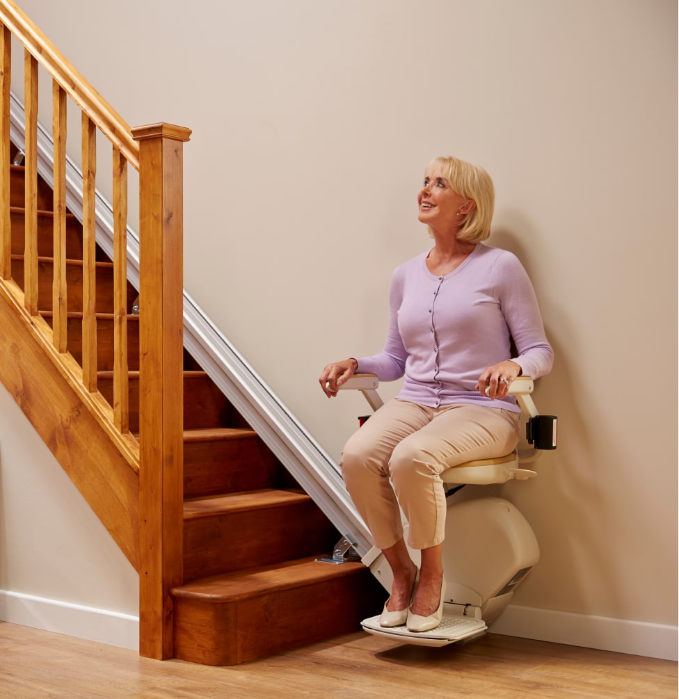 Mujer al pie de las escaleras en una silla elevadora mirando hacia arriba